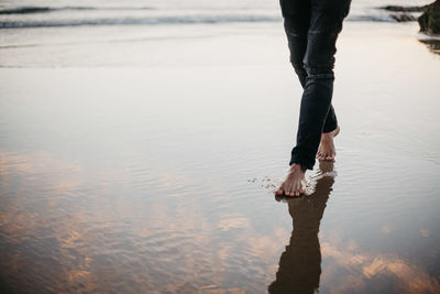 Low section of man standing on beach