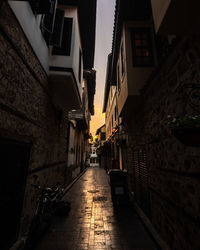 Empty alley amidst buildings in city at sunset