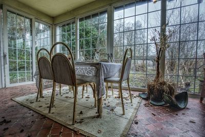 Empty chairs and table against window