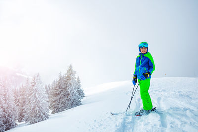 Man skiing on snow covered field against clear sky