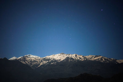 Low angle view of snowcapped mountain against blue sky