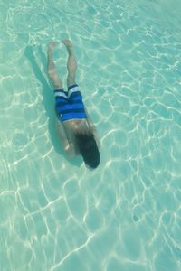 Rear view of young man swimming in pool