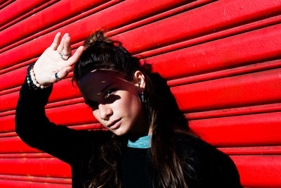 Portrait of beautiful young woman standing against corrugated iron