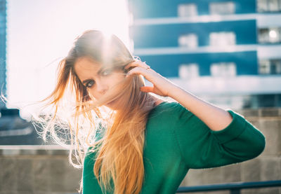 Portrait of young woman standing against buildings