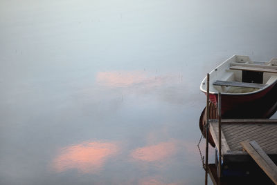 Rowboat moored at calm lake during sunset