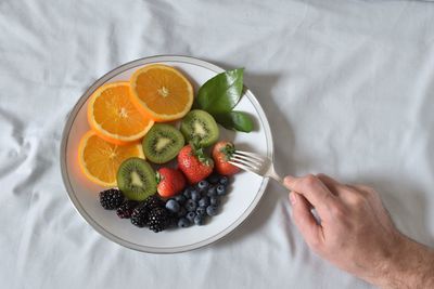 Close-up of hand holding fruit salad in plate