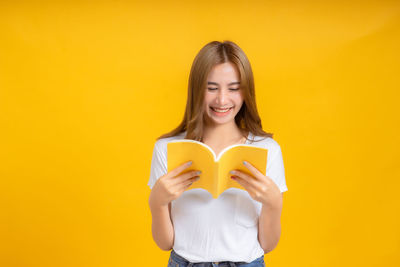 Portrait of a smiling young woman against yellow background