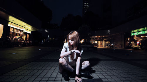 Woman sitting in illuminated city at night