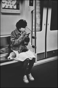 Side view of woman sitting on train window