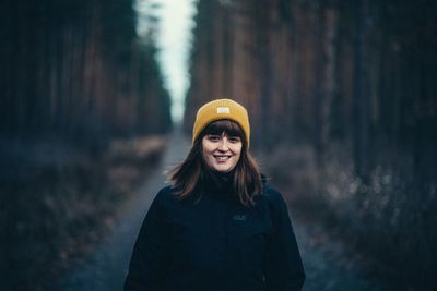 Portrait of smiling young woman standing in forest