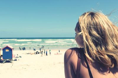 Rear view of woman at beach against clear sky