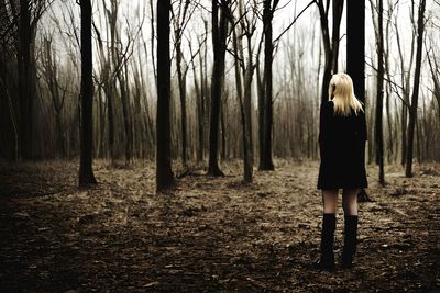 Rear view of woman standing in forest