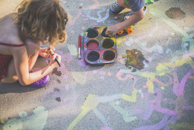 High angle view of playful siblings painting on road