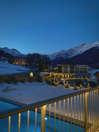 Illuminated buildings by mountains against clear blue sky during winter