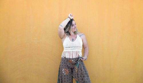 Portrait of happy girl dancing flamenco dance against yellow wall