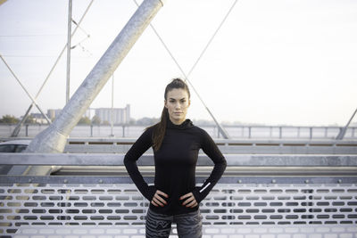 Portrait of woman standing on railing against sky