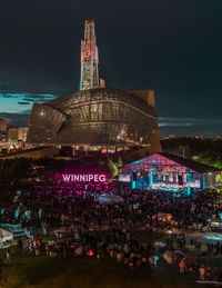 Crowd at illuminated building against sky at night