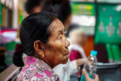 Side view of wrinkled senior woman sitting at home