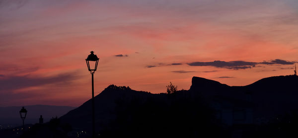 Silhouette street light against orange sky