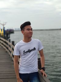 Young man standing in sea against sky