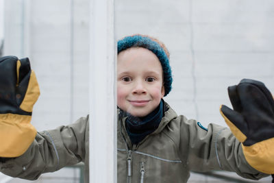 Boy leaning against a window smiling and looking in winter