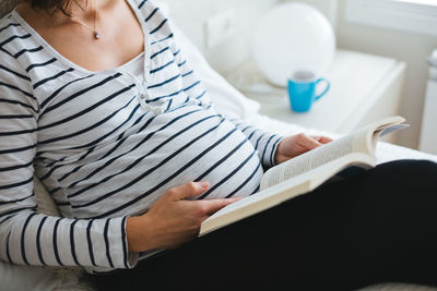 Midsection of boy holding book at home