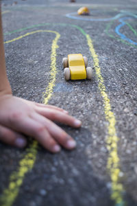 Cropped child by toy cars on road