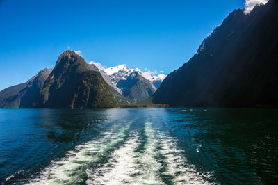 Scenic view of sea and mountains against clear blue sky