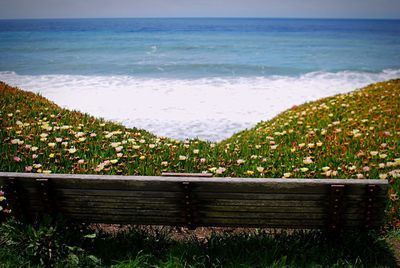 Empty bench in front of sea against clear sky