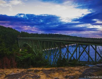 Bridge over river against cloudy sky