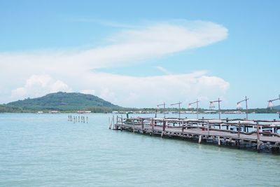 View of boats moored at harbor against cloudy sky