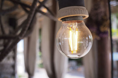 Close up image of light bulb, hanging from wooden ceiling