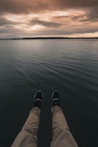 Low section of man standing on lake against sky