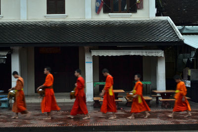 Rear view of people walking on street against buildings