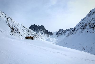 Built structure on snowcapped mountains against sky