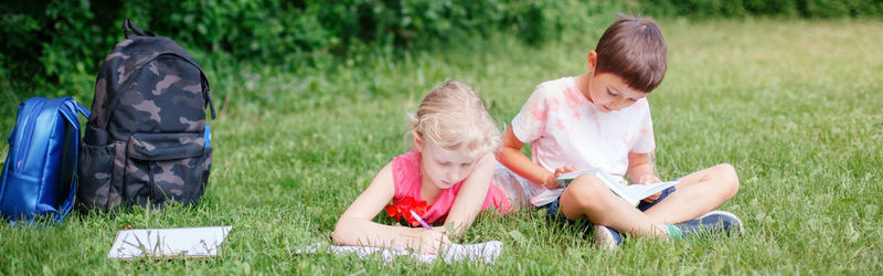 Cute kids studying sitting on grass