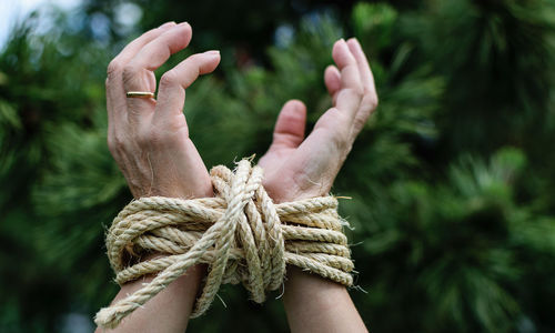 Close-up of human hand against rope