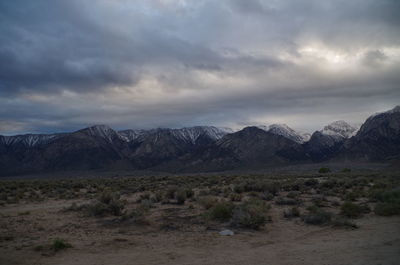 Scenic view of landscape and mountains against cloudy sky at dusk