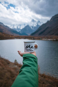 Hand holding lake against mountain range