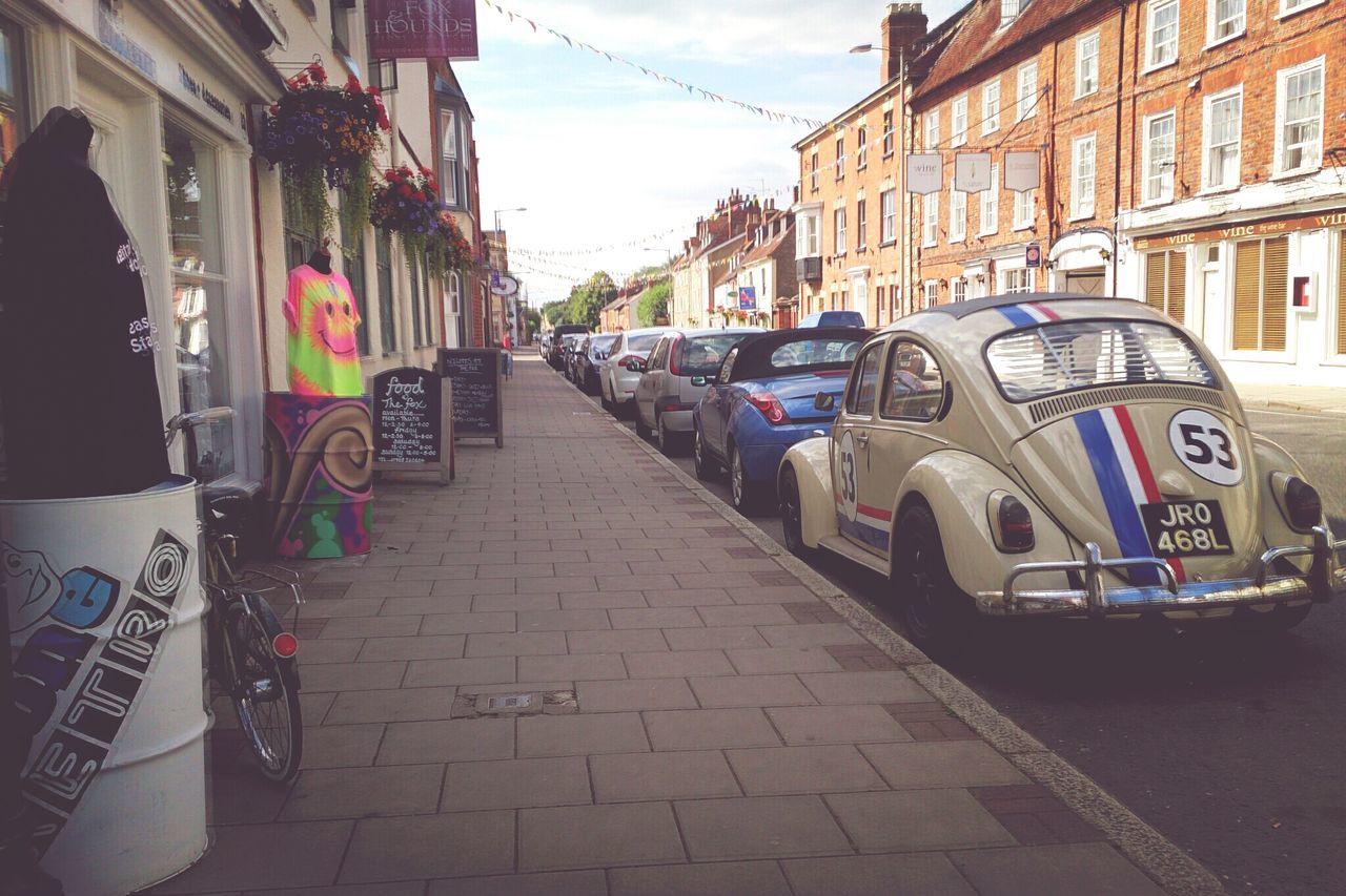 architecture, building exterior, built structure, transportation, street, city, mode of transport, building, land vehicle, car, sky, residential building, the way forward, residential structure, day, road, outdoors, diminishing perspective, cobblestone, city life