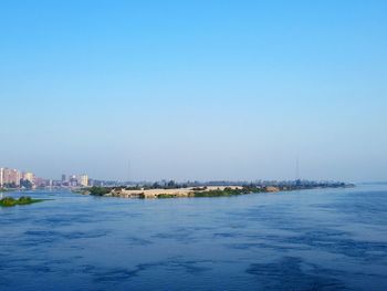 Scenic view of sea and buildings against clear blue sky