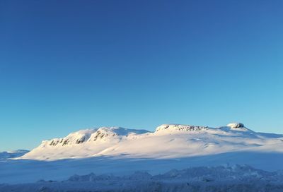 Scenic view of snowcapped mountains against clear blue sky