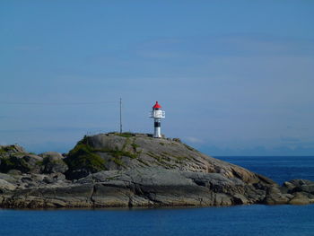 Lighthouse by sea against sky