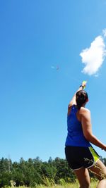 Rear view of woman holding umbrella against blue sky