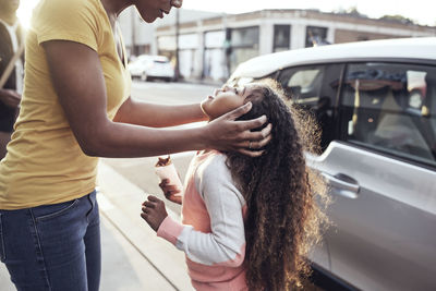 Girl looking at mother while standing at sidewalk