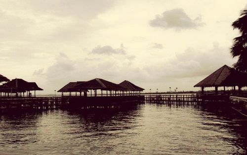 Pier on sea against cloudy sky