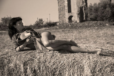 Full length of sensual woman lying on field