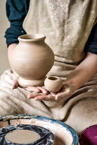 Sculpt man potter holds palms just made pitchers of different sizes. potter holds made pots.  