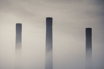 Low angle view of smoke emitting from chimney against sky