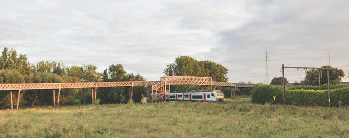 Train by trees on landscape against sky